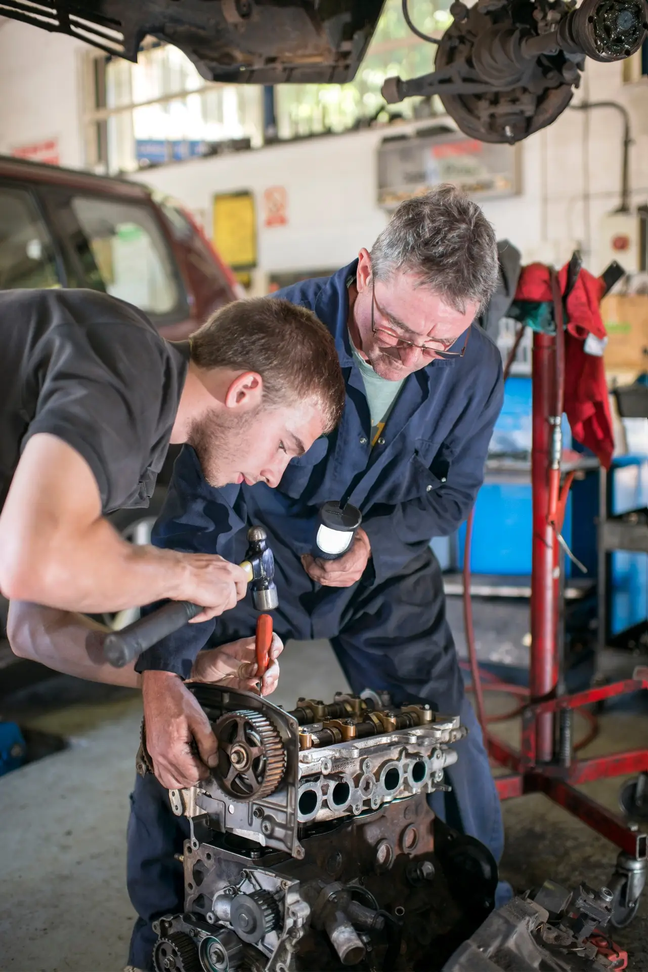 Mechanics working on car engine in garage
