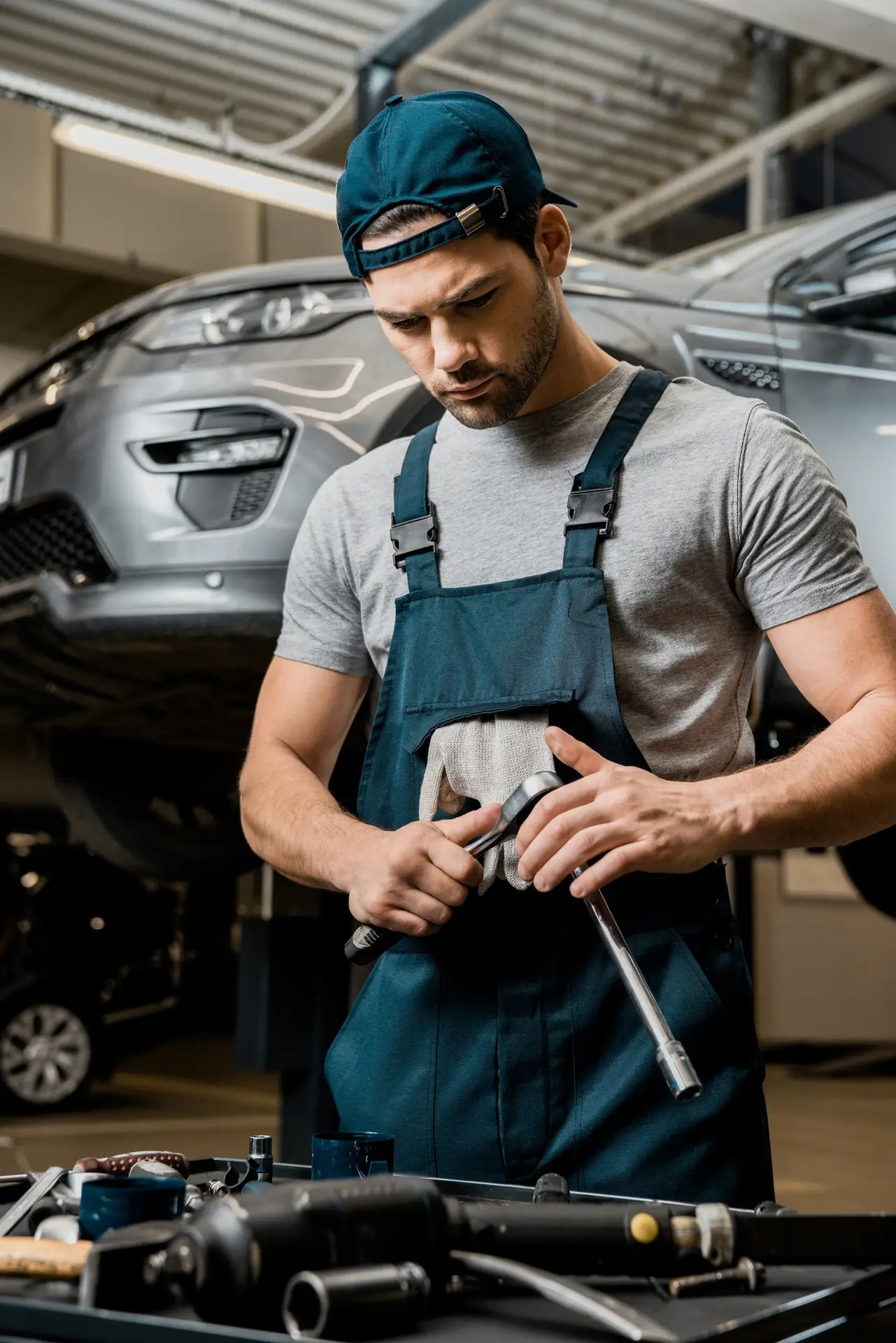 portrait of auto mechanic in uniform with lug wrench at auto repair shop